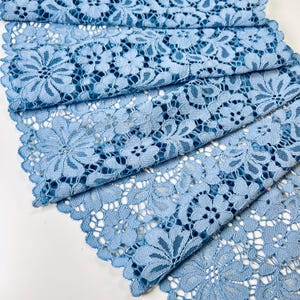 May include: Light blue lace fabric with a delicate floral pattern. The lace is soft and flowing, making it perfect for a variety of crafting projects.