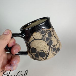 Taza de 295 ml con diseño de calaveras y borde brillante.