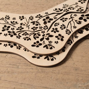 May include: Two wooden sock blockers with a floral design. The blockers are made of light wood with a dark brown floral pattern.