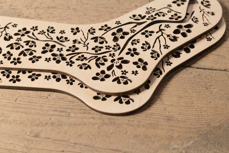May include: Two wooden sock blockers with a floral design. The blockers are made of light wood with a dark brown floral pattern.