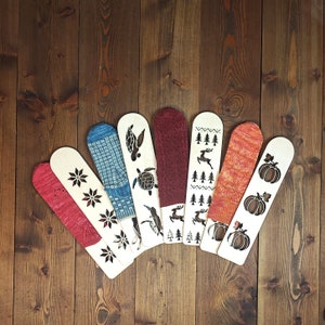 May include: Eight wooden craft sticks with various designs, including a turtle, a deer, a pumpkin, and a snowflake. The sticks are painted in shades of blue, red, and white.