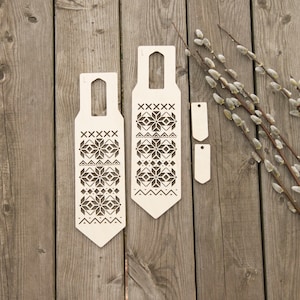 Könnte beinhalten: Zwei Holzausschnitte mit einem geometrischen Muster, das an ein skandinavisches Design erinnert. Die Ausschnitte befinden sich auf einem Holzgrund mit einem Zweig Weidenzweigen.