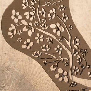 May include: A wooden cutout of a foot with a floral design. The design features delicate flowers and branches, creating a intricate pattern.