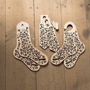 May include: Set of six wooden sock forms with a floral pattern. The forms are designed to help keep socks in shape and prevent them from getting stretched out.