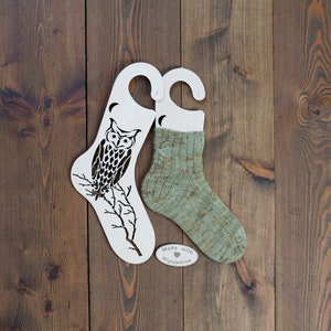 May include: Two wooden sock blockers with an owl design and a pair of green hand-knitted socks. The socks are on the blockers and there is a small tag that says "Made with love Mlynjadrow".