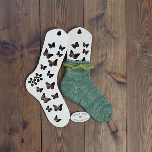 Può includere: Due blocca calze in legno con tagli a forma di farfalla, uno con un calzino verde. I blocca calze sono fatti con amore da Miynjedrow.