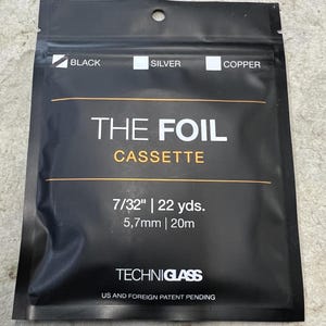 May include: A black rectangular foil cassette pouch by Techniglass. The label reads THE FOIL CASSETTE with color options for black, silver, and copper. It specifies a width of 7/32 inches and a length of 22 yards, or 5.7mm and 20m.