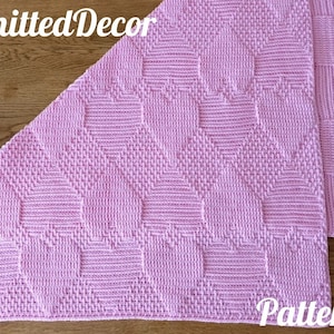 May include: A pink knitted baby blanket with a diamond pattern. The blanket is folded in half and the text "Knitted Decor Pattern" is visible.