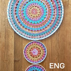 May include: Three colourful crochet dream catchers in shades of blue, pink, orange, and yellow. The largest is at the top, with two smaller ones below. The dream catchers are circular with intricate patterns.