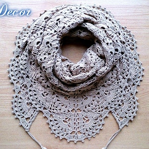 May include: A beige, crocheted scarf with a detailed, openwork design. The scarf is circular, with a scalloped edge and two tassels. The words "Knitted Decor" and "Pattern" are written in cursive.