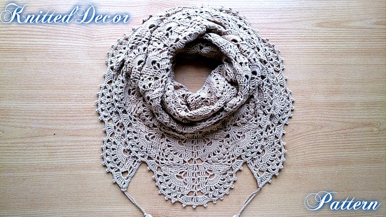 May include: A beige, crocheted scarf with a detailed, openwork design. The scarf is circular, with a scalloped edge and two tassels. The words "Knitted Decor" and "Pattern" are written in cursive.