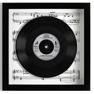 May include: A black vinyl record in a black frame with a white sheet music background. The record label says "Dexys Midnight Runners & The Emerald Express" and "Come On Eileen".
