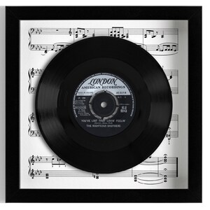 Op de afbeelding: Een zwarte vinylplaat in een zwart frame met een witte bladmuziek achtergrond. Het platenlabel zegt "London American Recordings" en "You've Lost That Lovin' Feelin' The Righteous Brothers".
