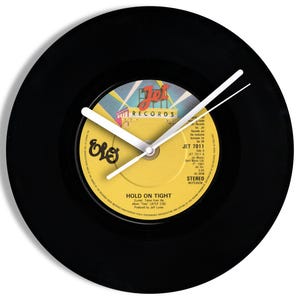 May include: Black vinyl record clock with white clock hands. The clock face is a yellow record label with the text "HOLD ON TIGHT" and the band name "ELO". The clock is round.