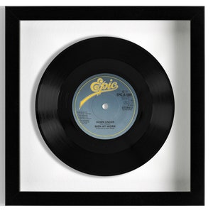 May include: A black vinyl record in a black frame with a white mat. The record label is for the song "Down Under" by Men at Work. The label is white with black text and a red and yellow Epic Records logo.