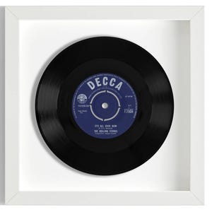 May include: A framed black vinyl record with a blue label. The label has the text "DECCA" in white and the song title "IT'S ALL OVER NOW" by "THE ROLLING STONES".