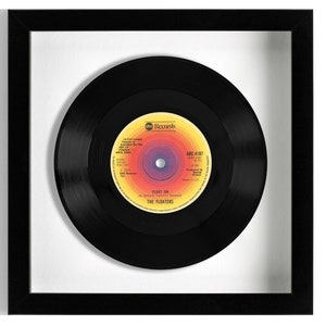 May include: A black vinyl record in a black frame with a white mount. The record label is yellow, orange, and purple with the text "ABC Records" and "ADC 4187" and "Fight On" by "The Floaters".
