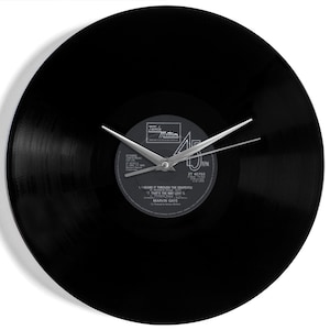 May include: A black vinyl record clock with silver hands. The clock face features the original record label with the text "Tamla Motown" and song titles. The clock hands point to 10:08.