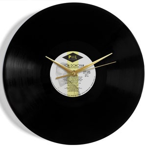 May include: A black vinyl record clock with gold hands. The record label features a photo of a man and the text "PWL Records, Jason Donovan,  'Every One I Love' 33 1/3 RPM,  HF 7".