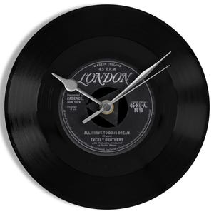 May include: A black vinyl record clock with silver hands. The clock face displays a record label with "LONDON" and "ALL I HAVE TO DO IS DREAM" by Everly Brothers. A decorative clock, perfect for music lovers.