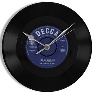 May include: A black vinyl record clock with silver clock hands. The clock face features a blue and white label with the text "DECCA" and "IT'S ALL OVER NOW" by The Rolling Stones.