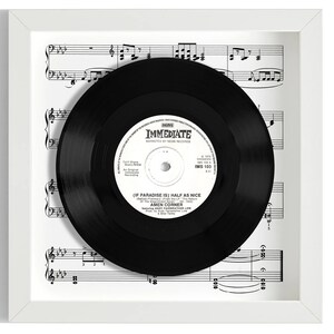 Op de afbeelding: Een zwarte vinylplaat in een wit frame met een blad muziek erachter. Het platenlabel zegt "IMMEDIATE" en "IF PARADISE IS HALF AS NICE" door AMEN CORNER.