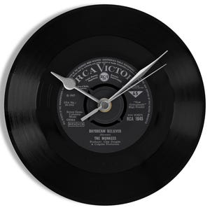 May include: A black vinyl record clock with silver clock hands. The record label features the text "RCA Victor" and the song title "Daydream Believer" by The Monkees. A unique wall clock for music lovers.