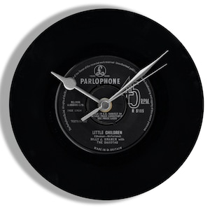 May include: A black vinyl record clock with silver clock hands. The record label reads "PARLOPHONE" and "LITTLE CHILDREN" by Billy J. Kramer and The Dakotas. The clock is a unique decorative item.