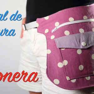 Puede incluir: Una riñonera de tela rosa con lunares blancos, con un bolsillo con cremallera y un bolsillo más pequeño con solapa. La riñonera se lleva alrededor de la cintura de una persona que lleva pantalones cortos blancos.