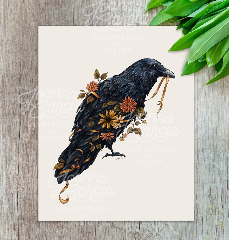 May include: A black raven with a golden ribbon in its beak, surrounded by a variety of autumnal flowers, including sunflowers, daisies, and orange blossoms. The raven is perched on a white background.