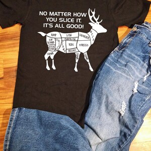 May include: A black t-shirt with a white graphic of a deer with different cuts of meat labeled. The text on the shirt reads "No matter how you slice it, it's all good!"