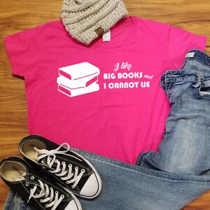May include: Pink t-shirt with a white graphic of stacked books and the text "I like big books and I cannot lie."