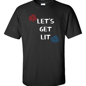 Op de afbeelding: Zwart T-shirt met witte tekst die "Let's Get Lit" zegt en rode en blauwe vuurwerkillustraties.