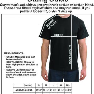 Op de afbeelding: Zwart T-shirt met een maattabel voor dameshemden. De gids bevat afmetingen voor borst, lichaamslengte en mouwlengte in inches. De tekst luidt "Maattabel voor dameshemden voor volwassenen."