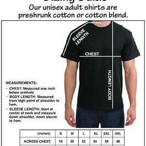 Op de afbeelding: Een zwart unisex T-shirt met een maattabel. De gids bevat metingen voor borst, lichaamslengte en mouwlengte in inches. De tekst luidt "Maattabel voor unisex shirts" en "Onze unisex shirts zijn van voorgekrompen katoen of katoenmix."