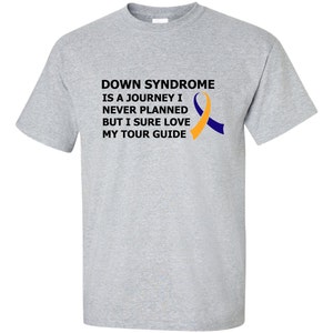Op de afbeelding: Grijs T-shirt met de tekst "Down Syndrome is a journey I never planned but I sure love my tour guide" en een geel en blauw lint.