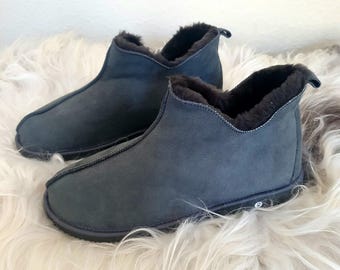 May include: A pair of dark charcoal gray ankle boots featuring a smooth matte exterior finish, a center seam detail running from the toe to the collar, and a thick dark brown faux fur lining that extends over the top edge of the boot opening.