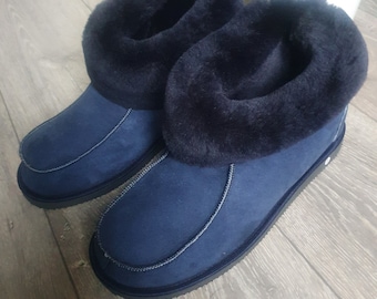 May include: A pair of blue suede slippers with black faux fur lining. The slippers have a rounded toe and a flat sole.