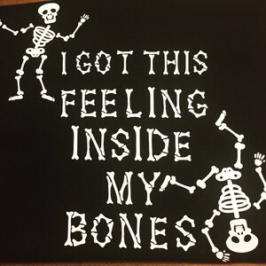 May include: Black and white graphic design with two skeletons. The text reads "I got this feeling inside my bones".