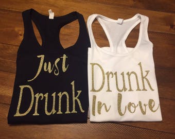 May include: Two tank tops with gold glitter lettering. One black tank top says "Just Drunk" and the other white tank top says "Drunk in Love".