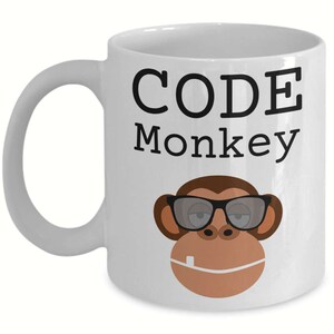 May include: White ceramic coffee mug with the text "CODE Monkey" in black lettering. A cartoon monkey wearing sunglasses is below the text.