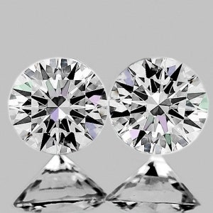 May include: Two round, brilliant cut diamonds, set on a white background.