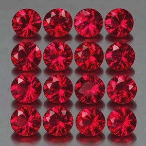May include: A collection of sixteen round, faceted red gemstones arranged in a four-by-four grid. Each stone features a brilliant cut with multiple triangular facets that reflect light, creating a vibrant, deep red color throughout the set.