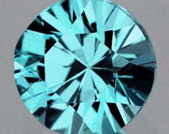 Puede incluir: Una gema redonda y facetada. La gema es de un color turquesa claro y vibrante, con facetas afiladas y reflectantes que crean un patrón de estrella. La gema se encuentra sobre un fondo neutro.