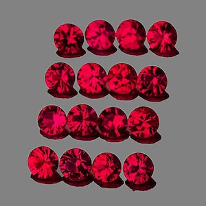 May include: A collection of fourteen faceted, round, red gemstones. Each gem has a complex, multi-faceted surface that reflects light, creating a brilliant sparkle. The gems are arranged in four rows against a gray background.