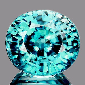 May include: A vibrant blue-green gemstone with a faceted oval shape. The gem has a complex, starburst-like pattern of facets.