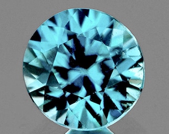 Puede incluir: Una piedra preciosa redonda y facetada con un patrón de color azul y negro. La piedra preciosa tiene un diseño de estrella.