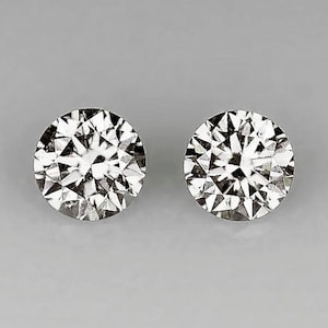 May include: Two round, brilliant-cut diamond studs. The diamonds are clear and faceted, reflecting light. The earrings are set against a gray background.