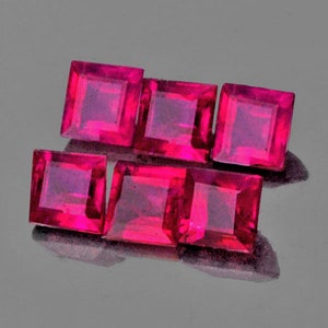 Può includere: Sei gemme rosa vivaci, tagliate a forma quadrata, sono disposte su una superficie riflettente. Le gemme presentano un colore intenso e saturo e un aspetto lucido, con sfaccettature visibili. La disposizione suggerisce una collezione di gemme sciolte.