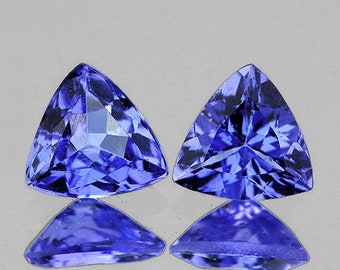 May include: Two triangular-shaped gemstones with a deep blue color. The gemstones are faceted and have a high level of brilliance.